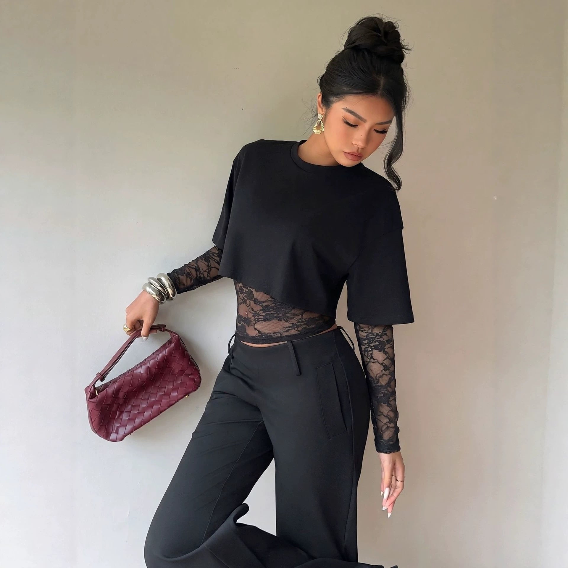 Svart topp med spetsdetalj i midjan i helbild, styled med svarta byxor