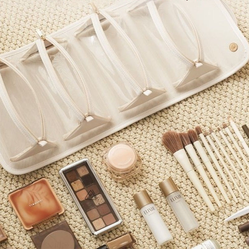 Beige necessär utrullad med sminkborstar och paletter
