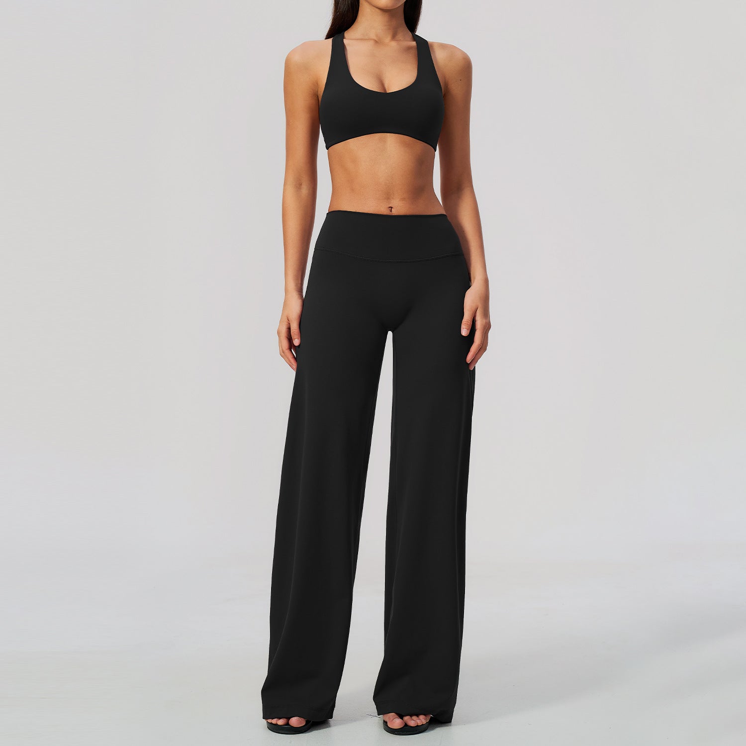 Svart yogaset med korsad topp och högmidjade vida byxor på modell