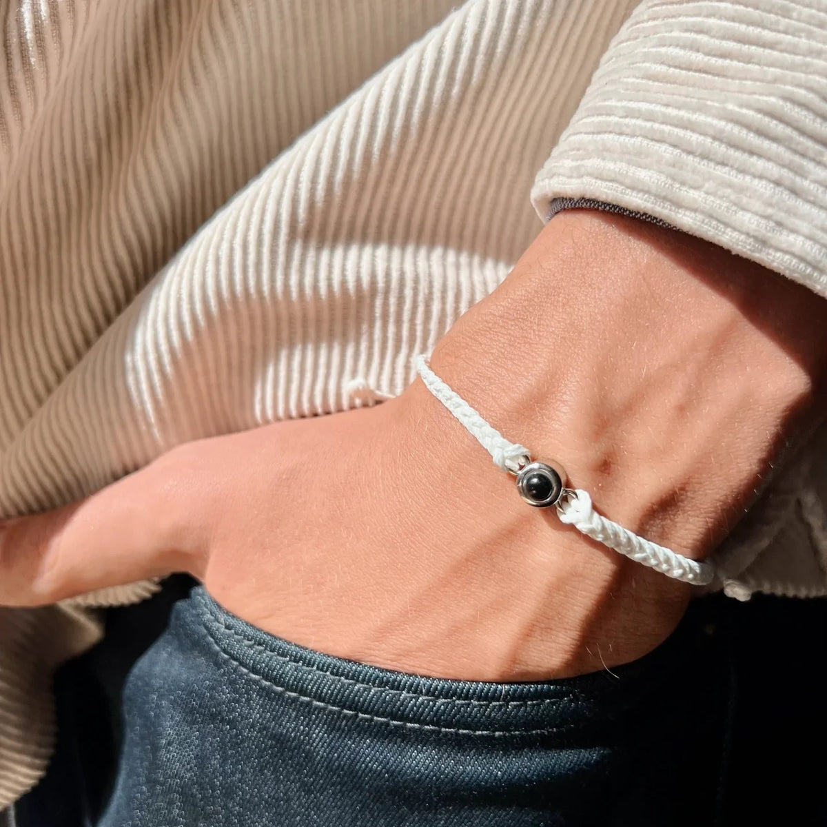 Fotoarmband på handled mot ljus stickad tröja