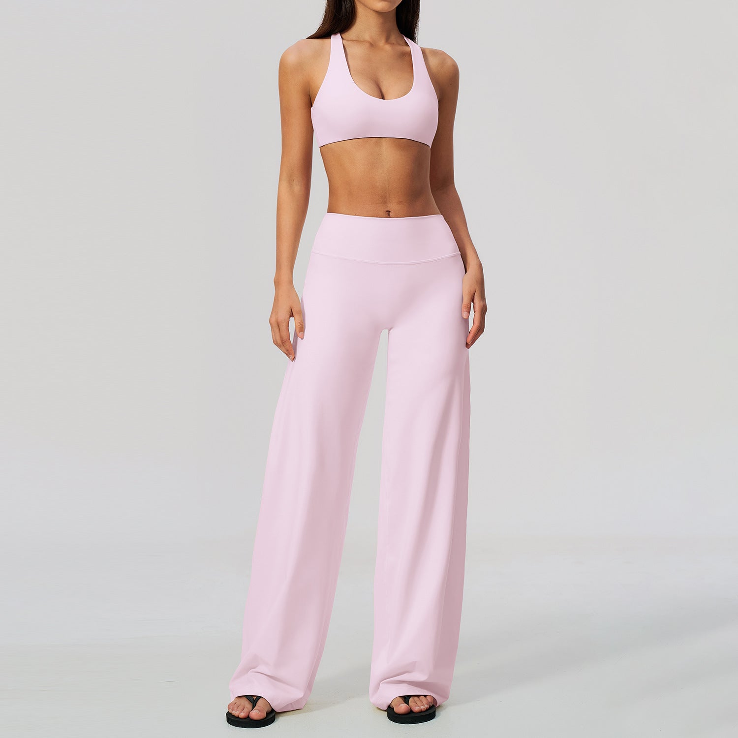 Ljusrosa yogaset med korsad topp och högmidjade vida byxor på modell