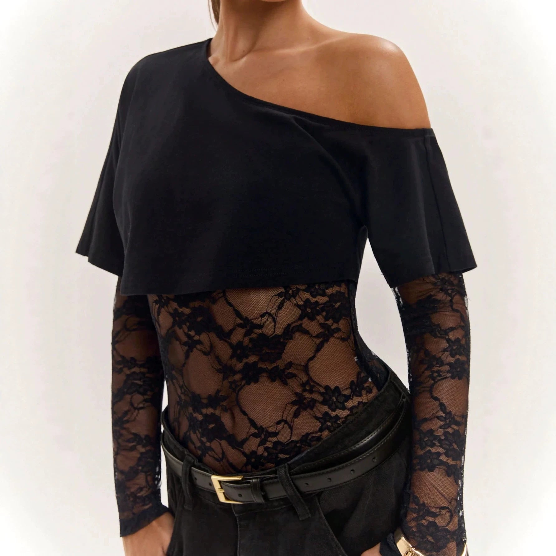 Närbild på svart spetsbodysuit styled med svarta byxor och skärp